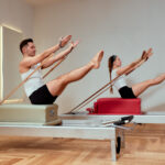 A man and a woman in a pair do pilates exercises on reformers, diversity man and woman, paired exercises on a reformer to restore the musculoskeletal system, pilate, reformer